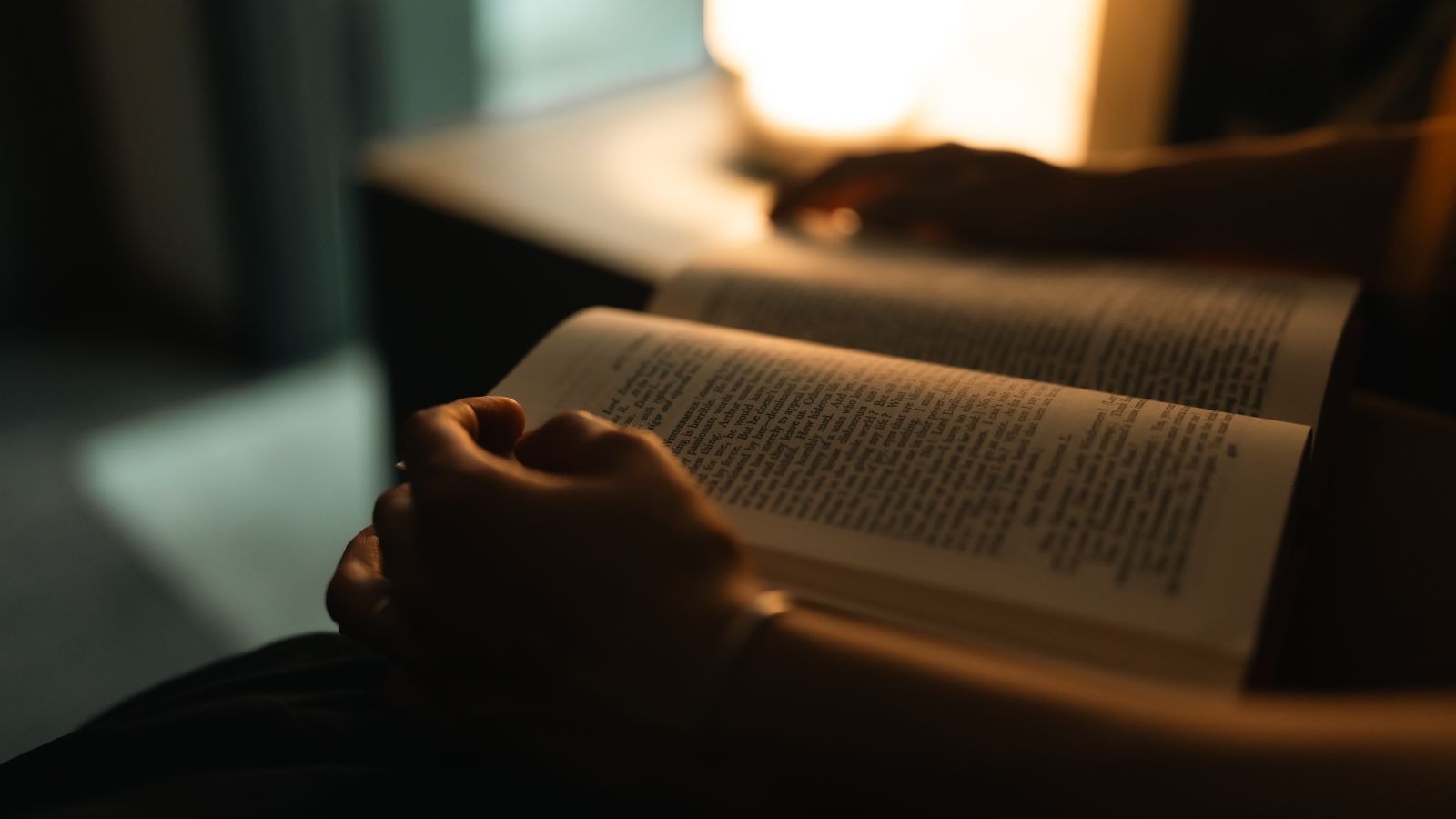 Personne assise en train de lire un livre le soir